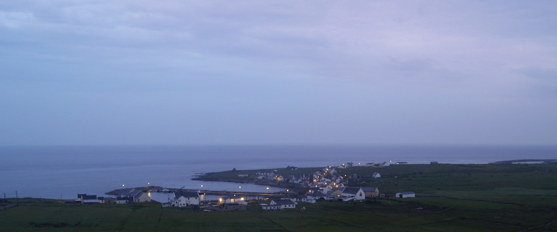Tory Island at dusk, the lights of West Town along the shore and the Atlantic beyond